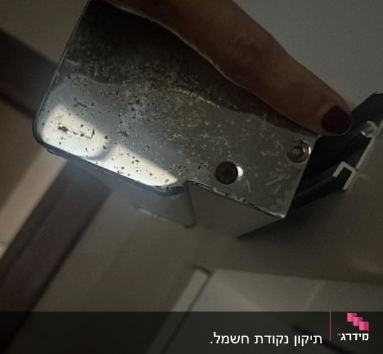 אדם מצביע על קופסת מתכת עם חוטים חשמליים